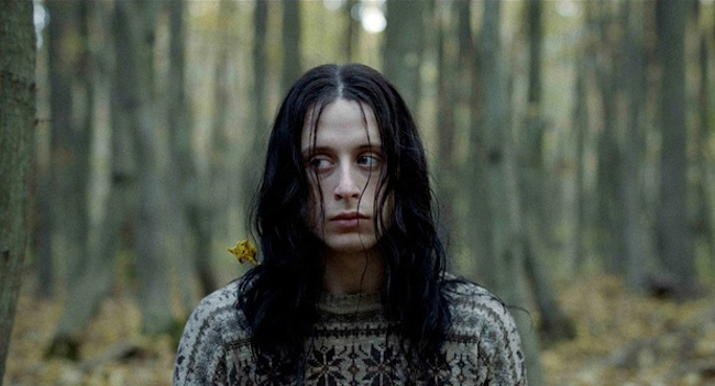 euronymous in a forest, with black hair and a sweater